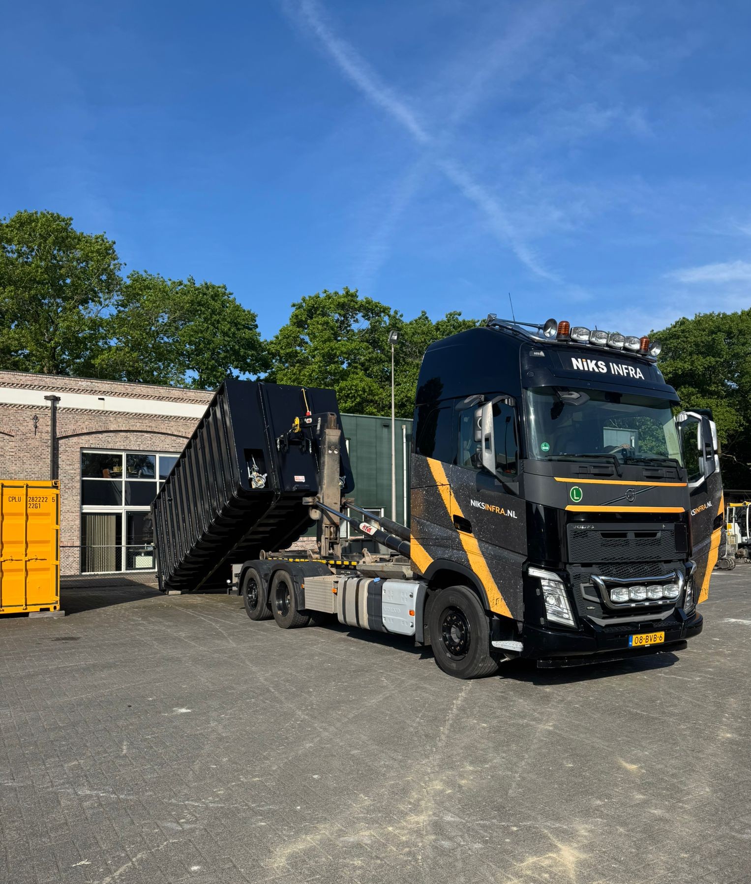 Vrachtwagen van Voor Niks Infra trekt vloeistofdichte container op voor transport